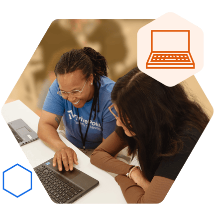 A staff member and a student are sitting at a table and smiling while working together on a laptop