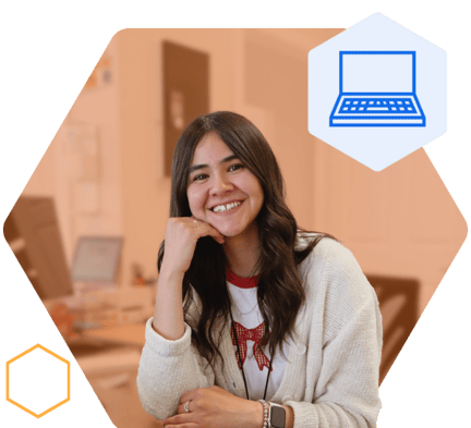 A staff member sitting at a desk and smiling at the camera with her hand under her chin