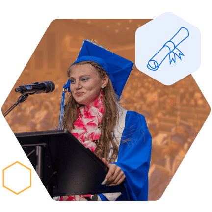 A student in a blue graduation cap and gown, standing at a podium and speaking into a microphone, giving a graduation speech