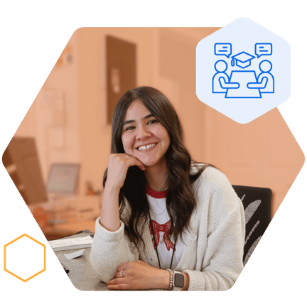 A staff member sitting at a desk and smiling at the camera with her hand under her chin
