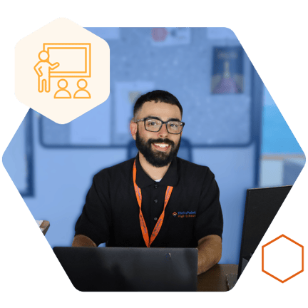 A staff member sitting at a desk and smiling while working on a laptop