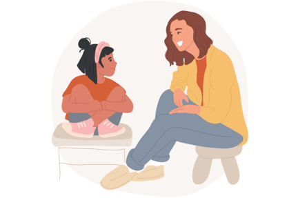 A student sitting on a stool next to an adult also sitting on a stool, smiling, talking, and listening to each other